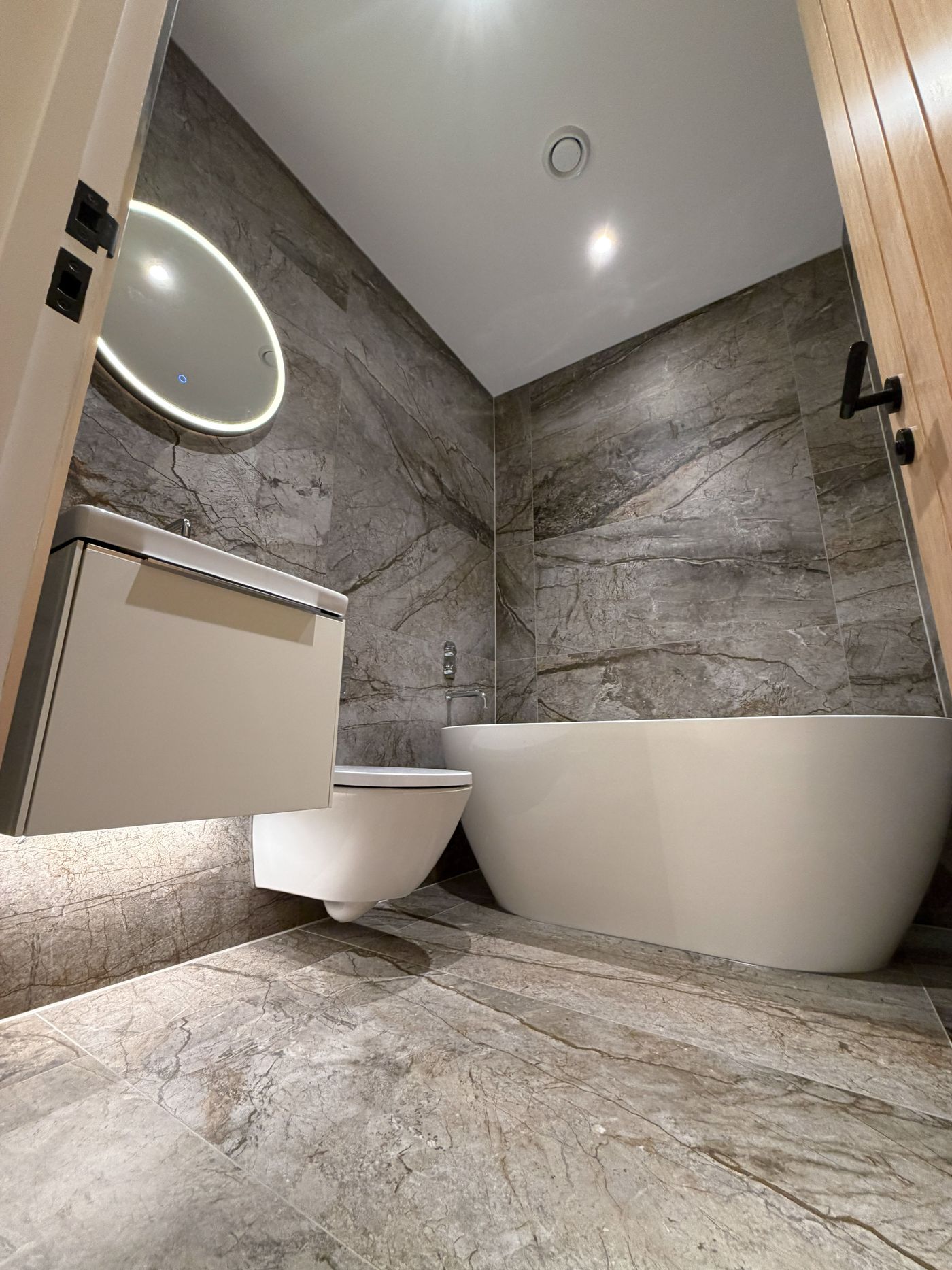 Bathroom with an illuminated mirror and freestanding bath