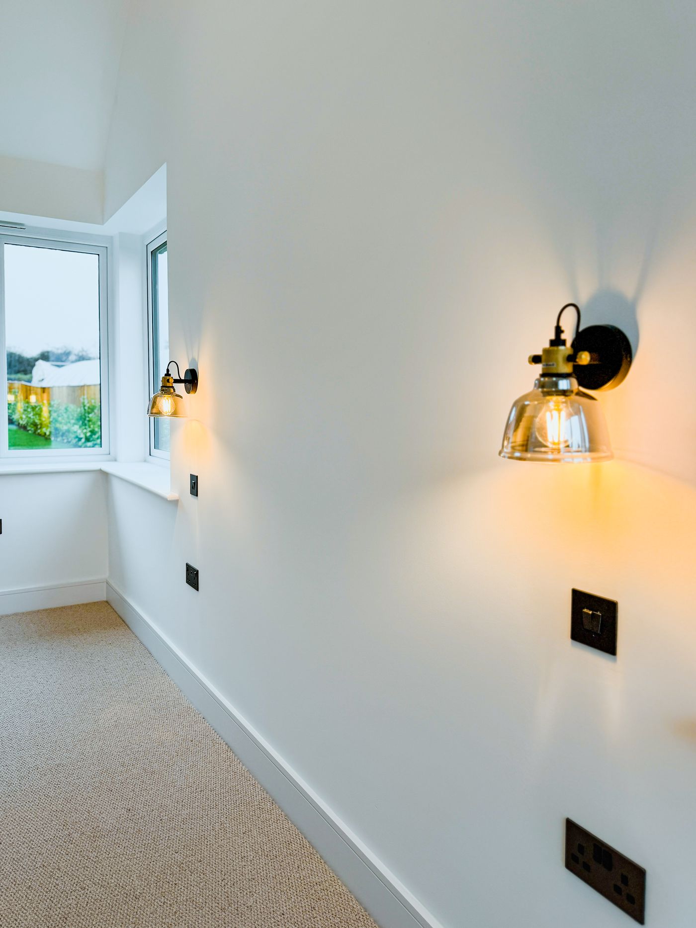 Bedroom with brass wall lights and black sockets