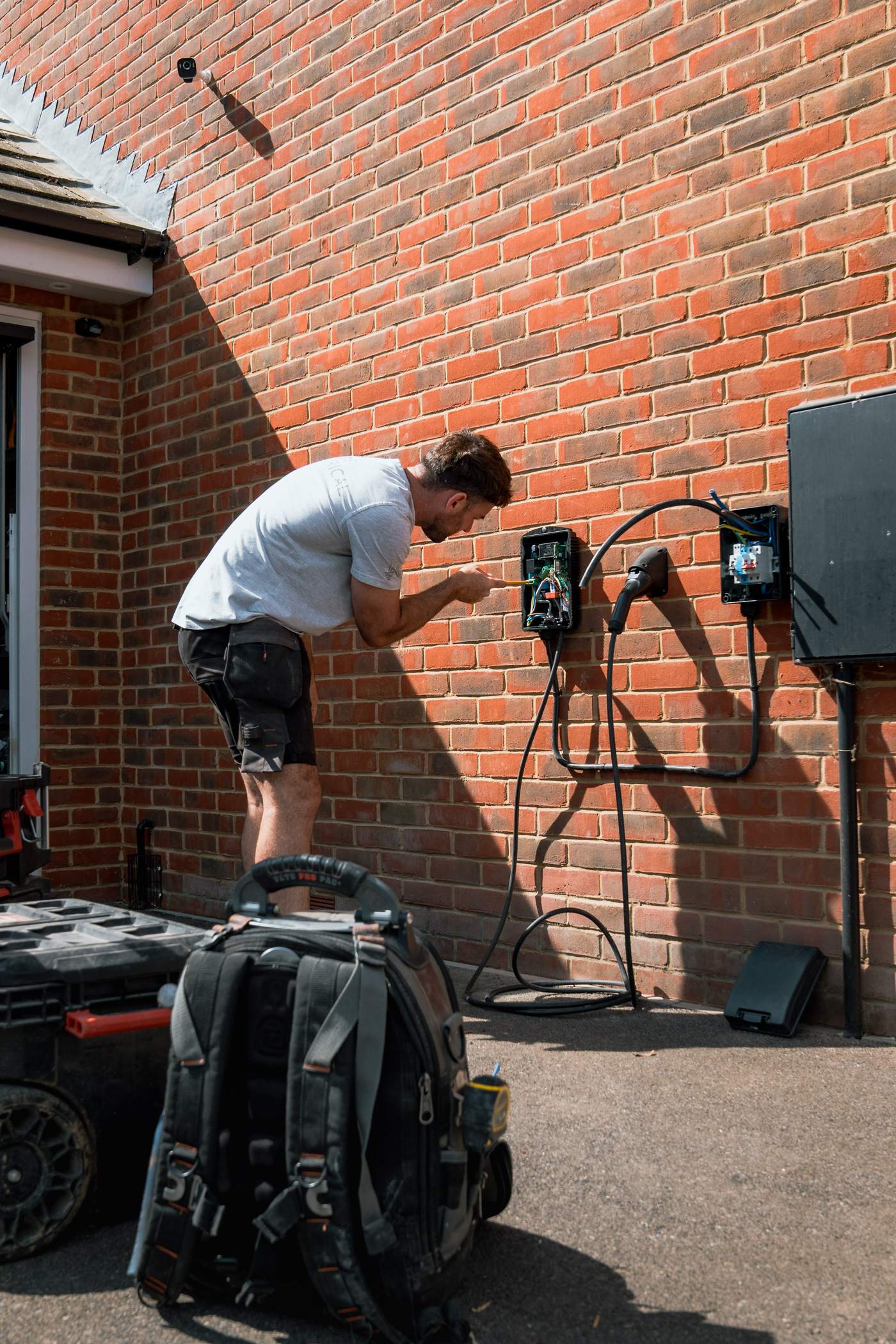 Tom on the steps fitting an EV charger to a house wall