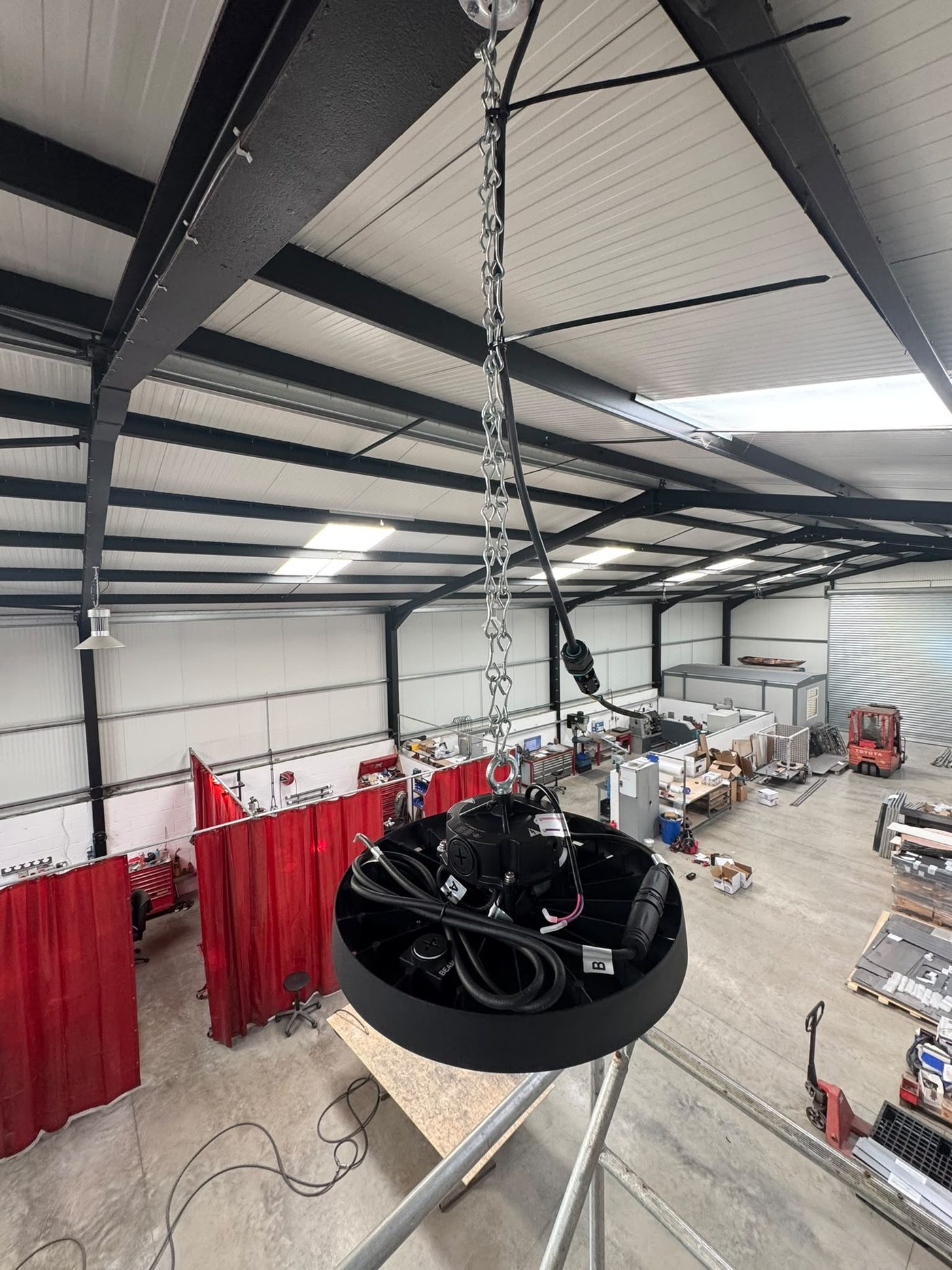 LED high bay light being installed in an industrial workshop